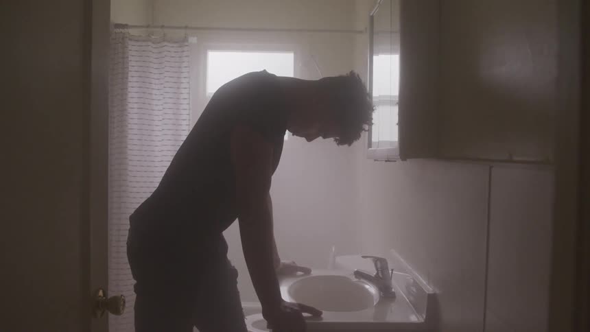 Silhouette of man reclining on bathroom sink