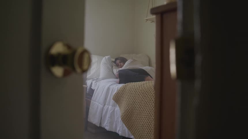 Woman sleeps in bed in her room during daylight