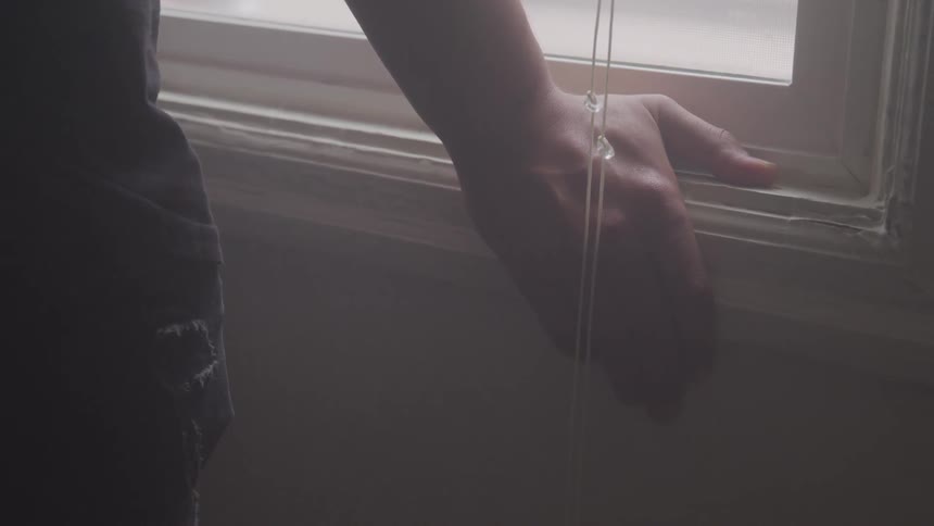 A person stands with their hand resting on a windowsill