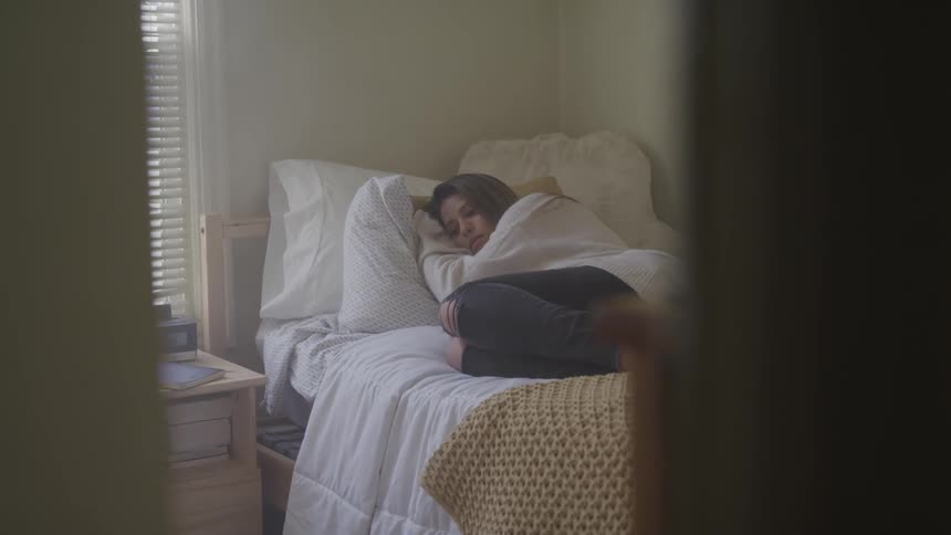 A teenager takes a nap in her bedroom