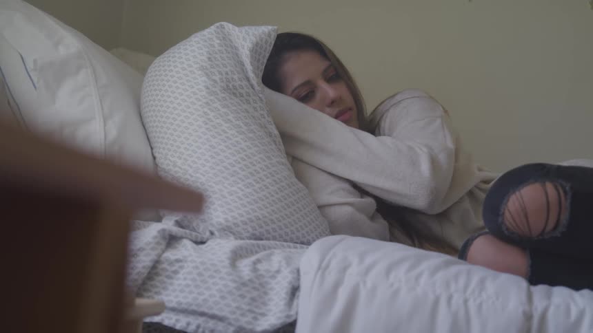 Woman moves a bit while she lays curled up in bed