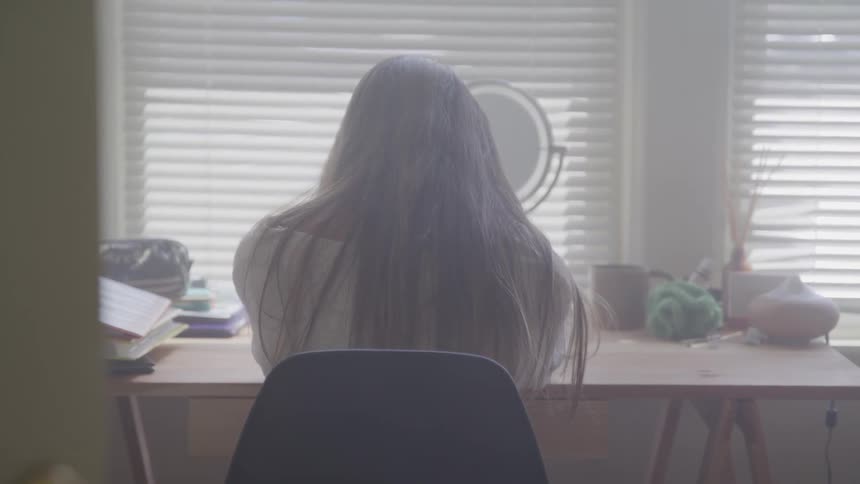 Woman sits at table in front of magnifying mirror