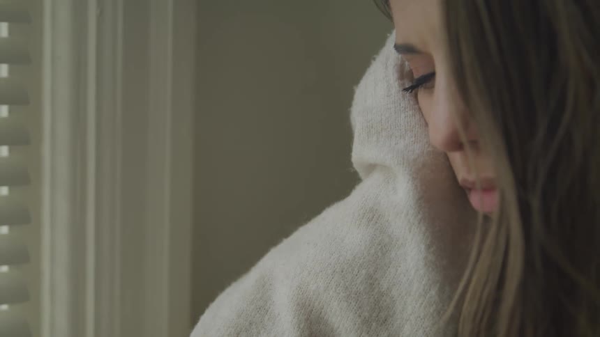 A white teenage girl wrapped in a blanket sits in a room