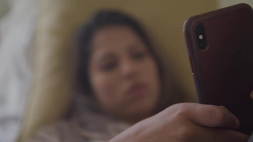 A female reclines while looking at the screen on her smart phone