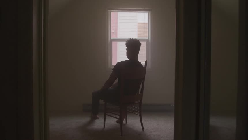 Man sits on straight chair in empty room