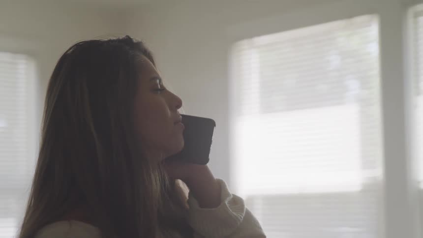 A teenager holds a smartphone up to ear and listens