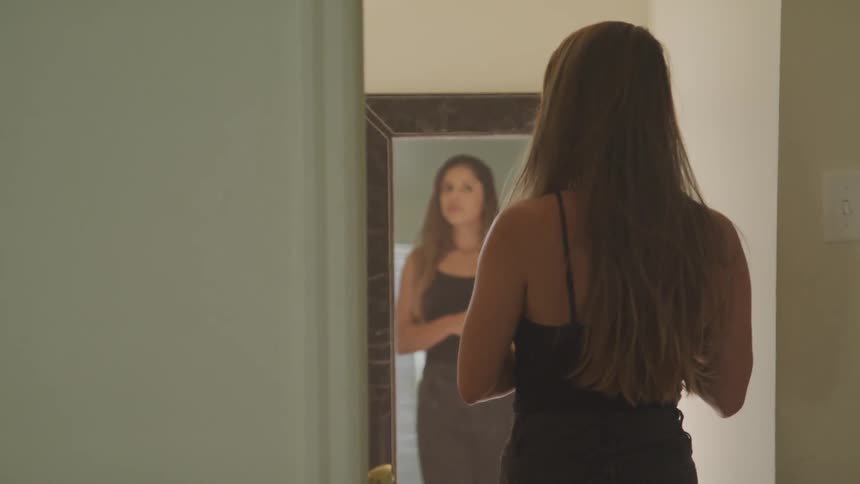 A woman playing with her hair in the mirror