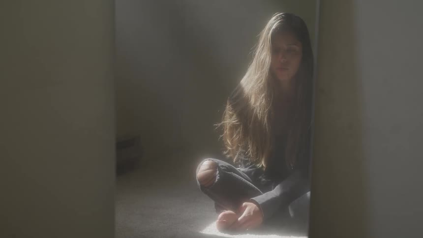 Woman sits cross legged in room under sun rays