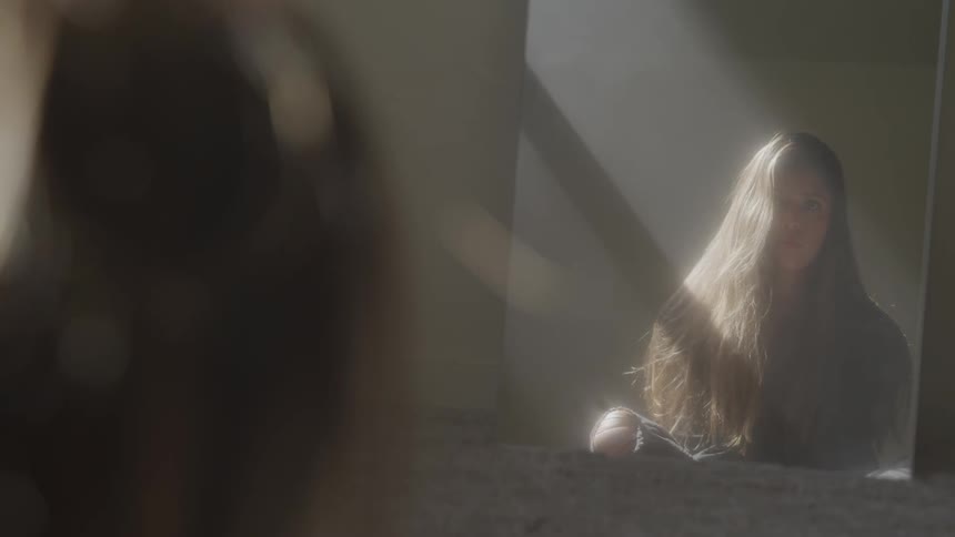A woman sitting in a room looking into a mirror