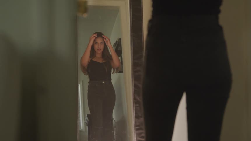 Brunette woman looks at herself in the mirror in a room