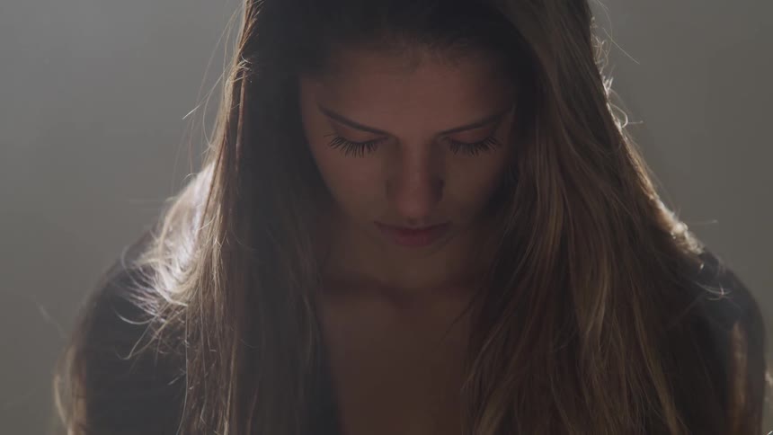 A female gazes at her shoes under a spotlight