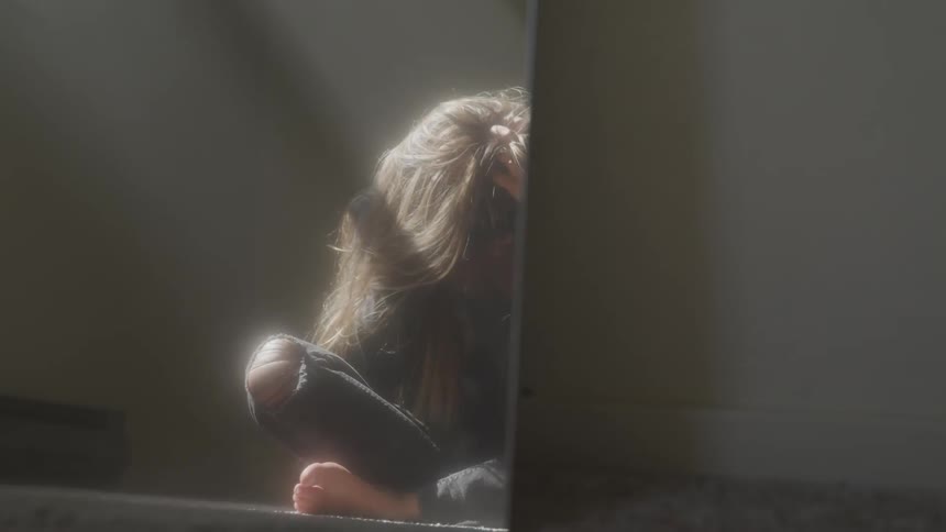 A sad blonde woman sit in a room
