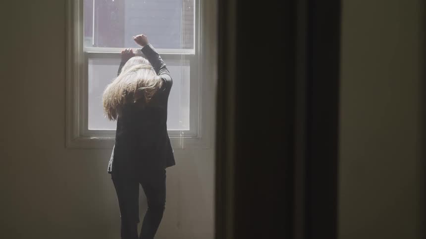 A white woman leans against a window