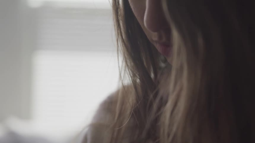 A womans long hair hangs around her face as she looks down