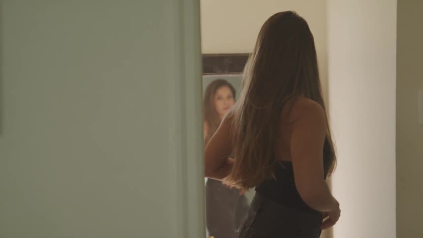 A woman checks her outfitin front of a full length mirror