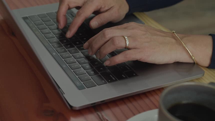 Woman types on laptop with coffee mug nearby