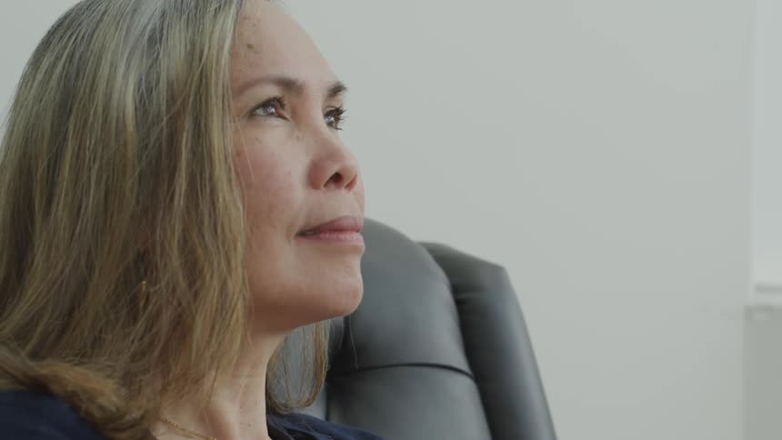A woman sits in a chair and looks ahead