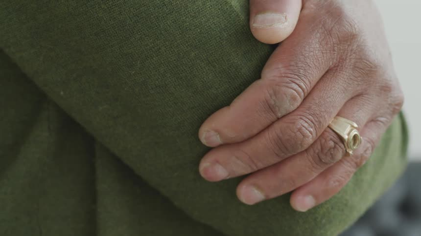 A man in a green sweater with his arms crossed