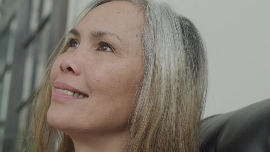 Woman sitting on couch looking up and smiling