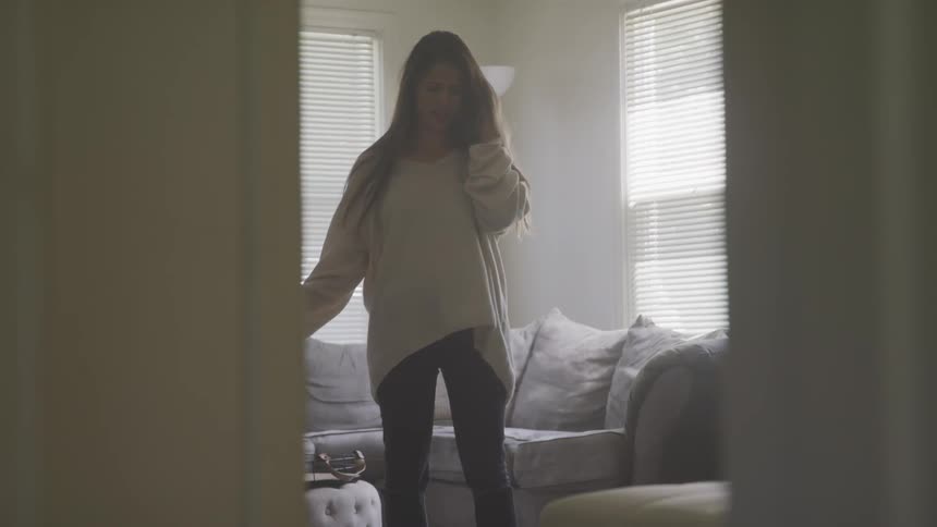 A woman gestures with one hand then covers her face as she talks on the phone