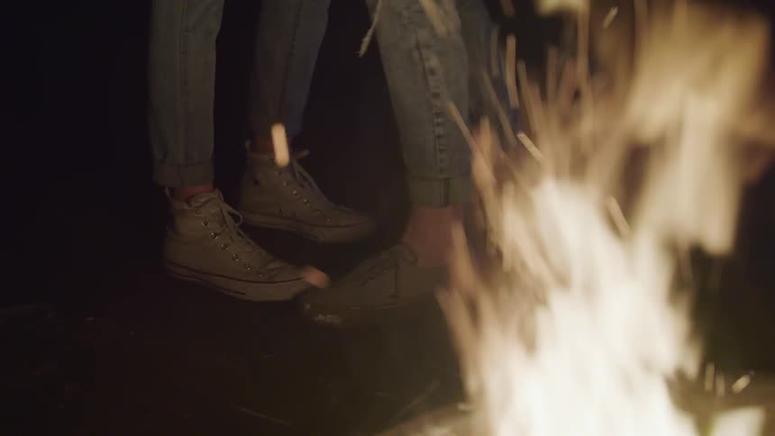 A young couple dancing by a fire