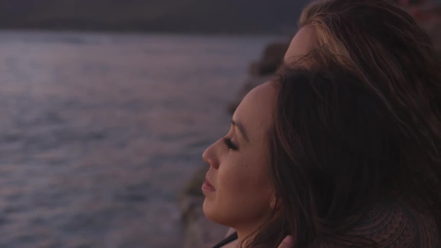 Two women sit together and look out at the water
