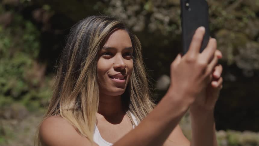 Woman holds a cellphone in front of her as she scrolls with her thumb