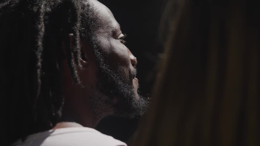 A black man smiles and look off in to the distance