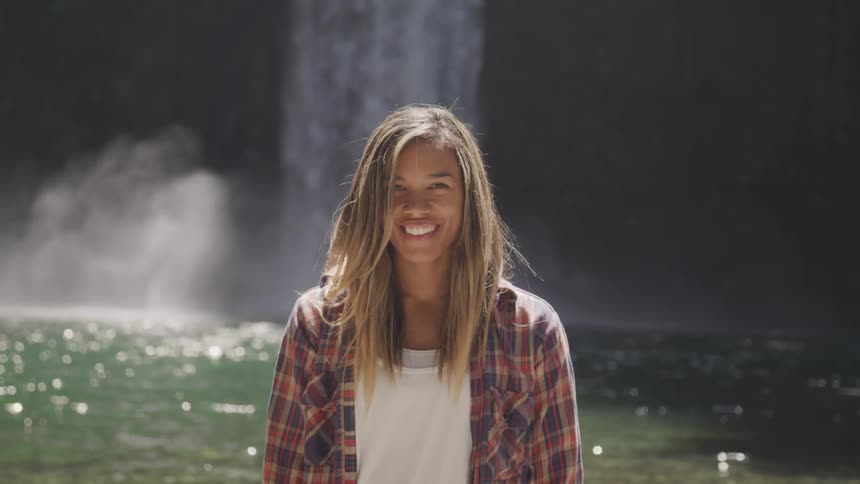 A woman is smiling by the waterfall