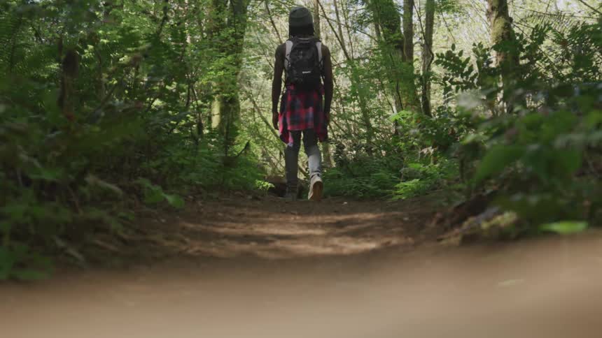 Man walks down dirt path in wooded area