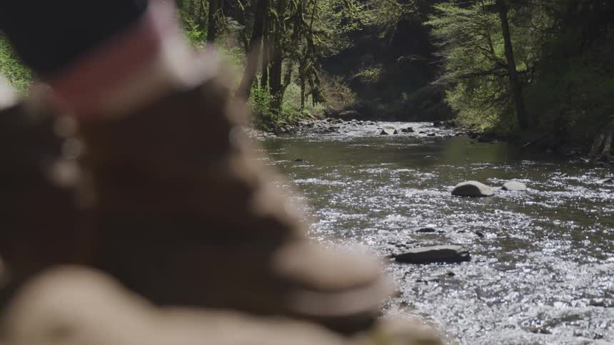 A persons feet with boots with a river in the background