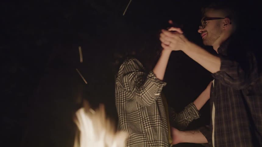 A young couple dancing next to a roaring fire