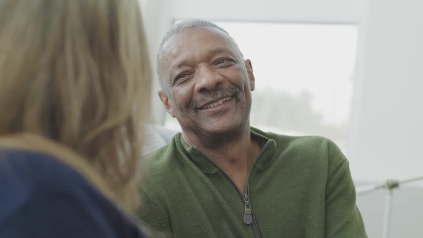 A black man smiles as he looks at the woman he is sitting with