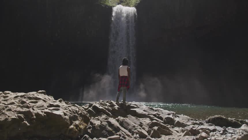 A man standing in front of a waterfall