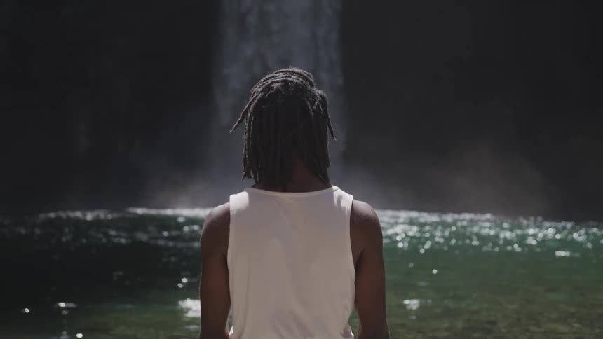 A person standing up looking at a waterfall