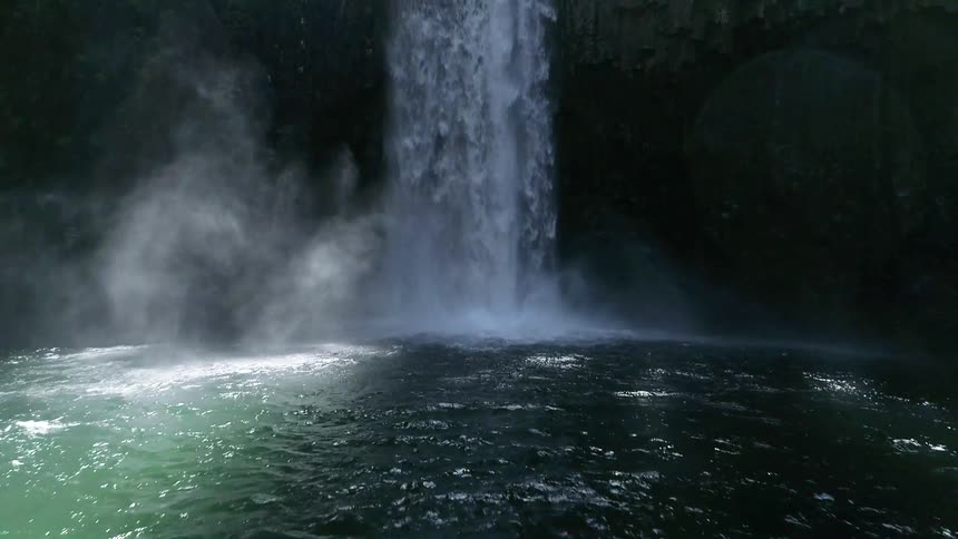 A waterfall flows into a body of water below in the wilderness