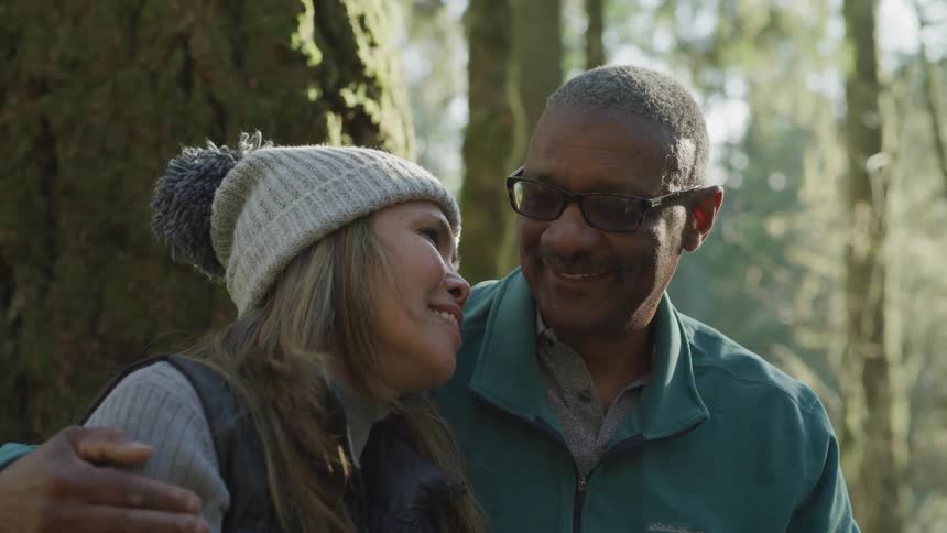 A black couple embrace out in the woods