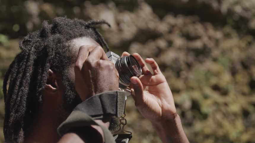 A man smiles after he puts his camera down after taking a photo outside