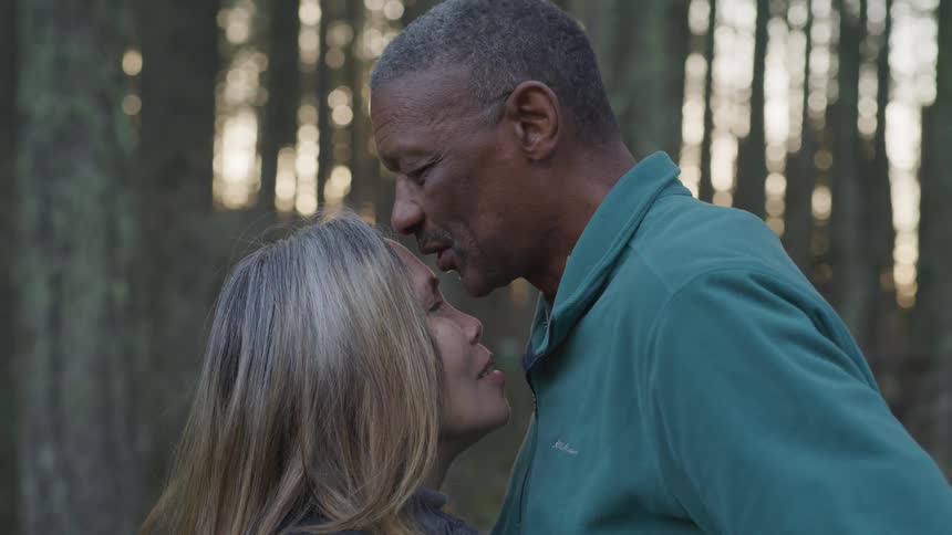 Husband kissing his wife on the forehead outdoor in the forest