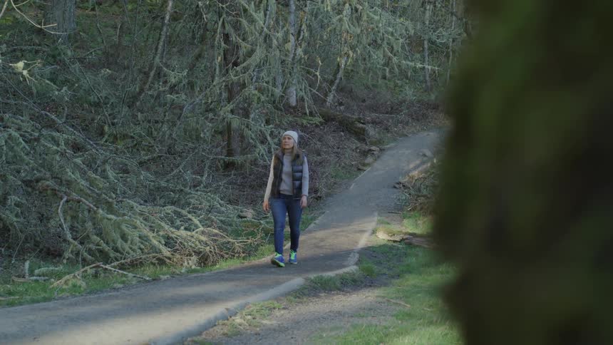 Woman walks on the cycle path in the forest