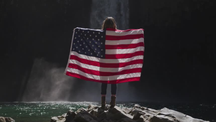 A woman stands with a flag against her back