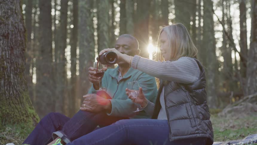 A woman pours wine in to a mans wineglass