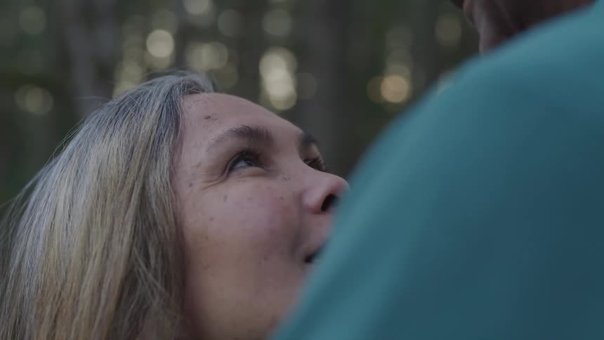 A woman looks up and smiles at her husband while they are embracing