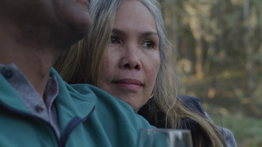 Blonde haired woman leans her head on the shoulder of a man wearing a green jacket