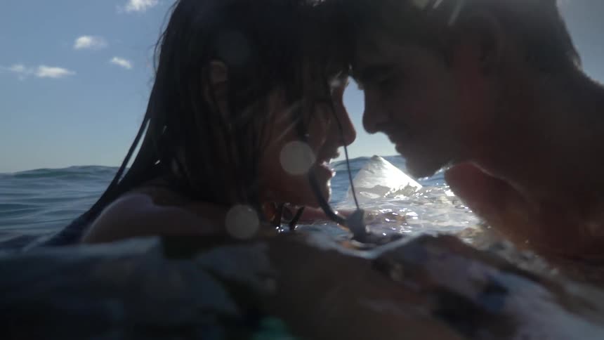 A man and woman hold on to one another and hug in the water