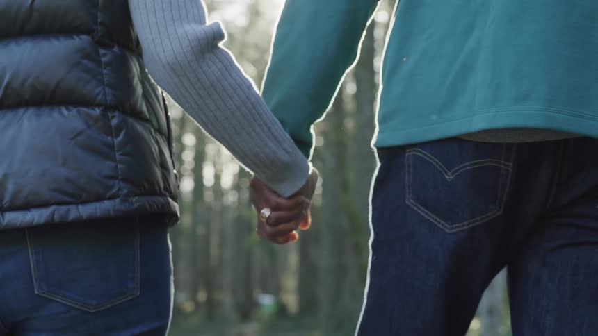 A man and a woman hold hands while walking outside