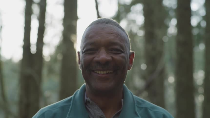 A black man smiles while standing outdoors