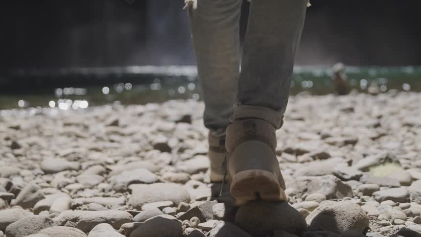 Man walks on the gravel to the waterfall
