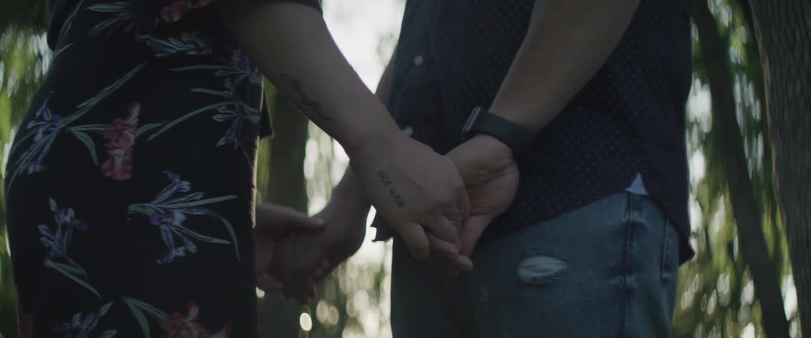 A man and woman stand together and hold hands
