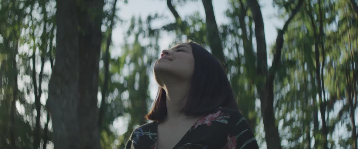 A woman looking up in a forest